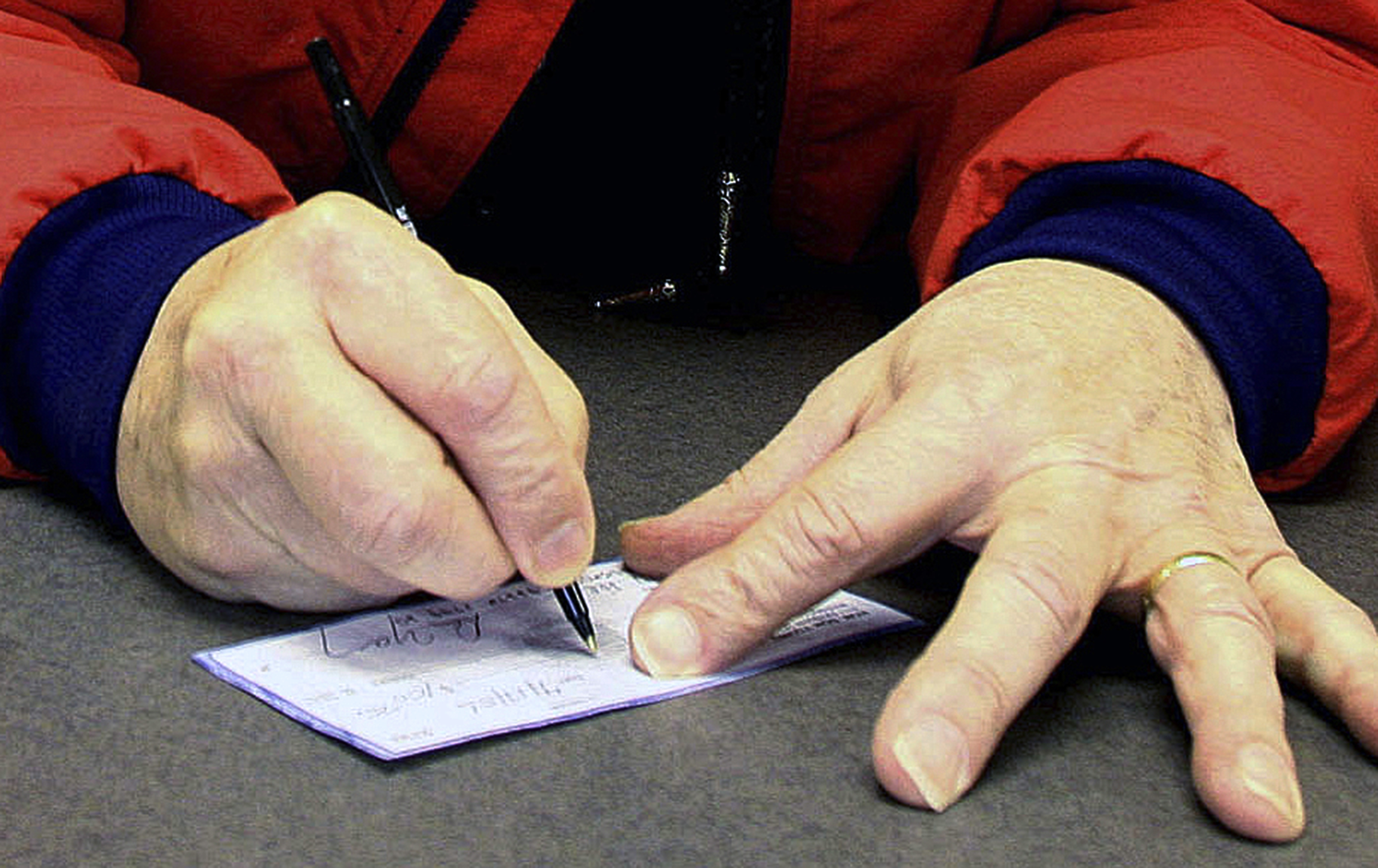FILE - A man signs a check in Anchorage, Alaska, April 17, 2006,. Check fraud tied to mail theft is up nationwide, according to a recent alert. The U.S. Postal Service is vulnerable, and thieves who can access your checks can change the amount and ferret those funds right out of your bank account. (AP Photo/Al Grillo, File)