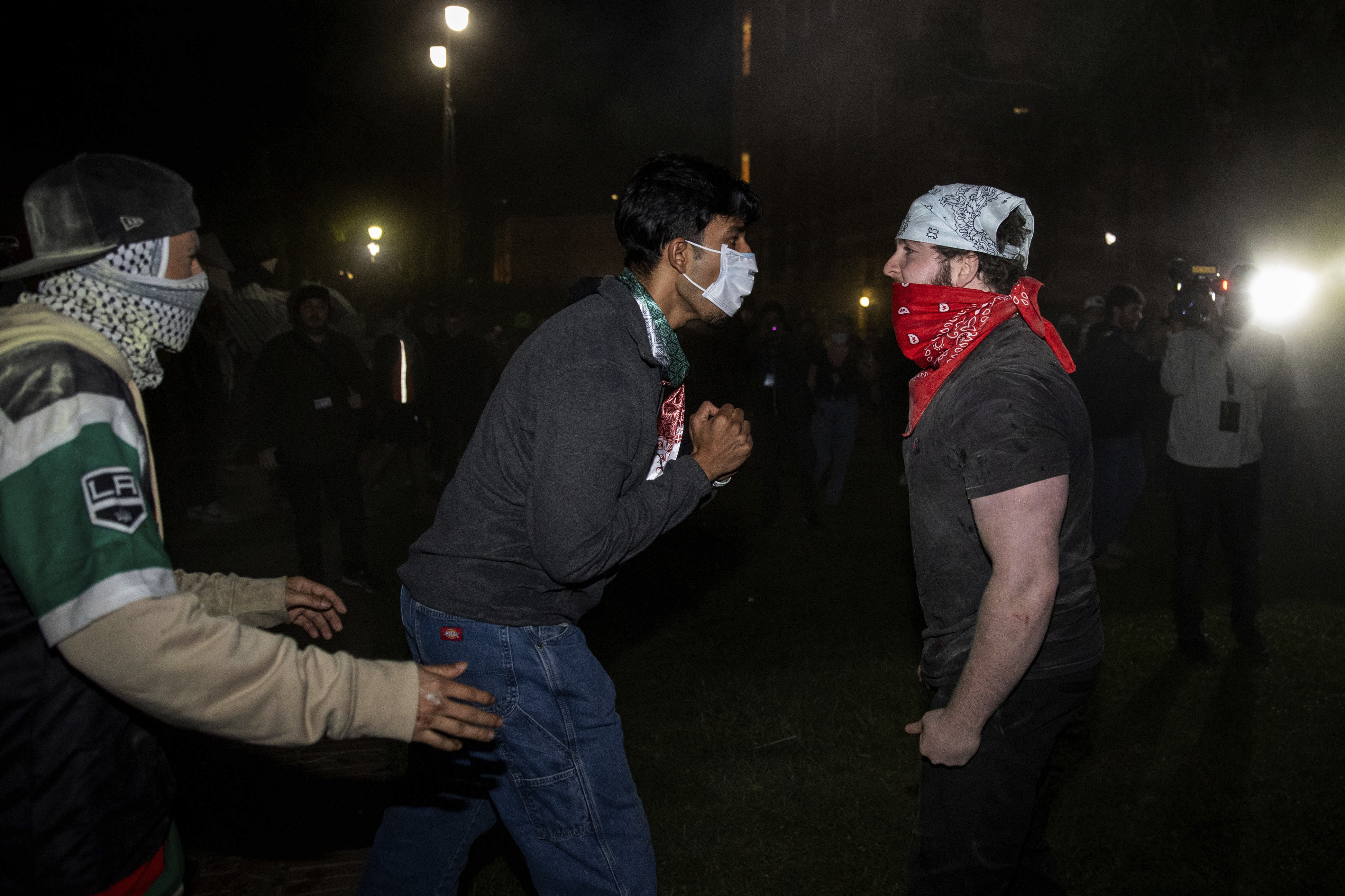 Demonstrators clash at a pro-Palestinian encampment at UCLA Tuesday, April 30, 2024, in Los Angeles. Dueling groups of protesters have clashed at the University of California, Los Angeles, grappling in fistfights and shoving, kicking and using sticks to beat one another. (AP Photo/Ethan Swope)