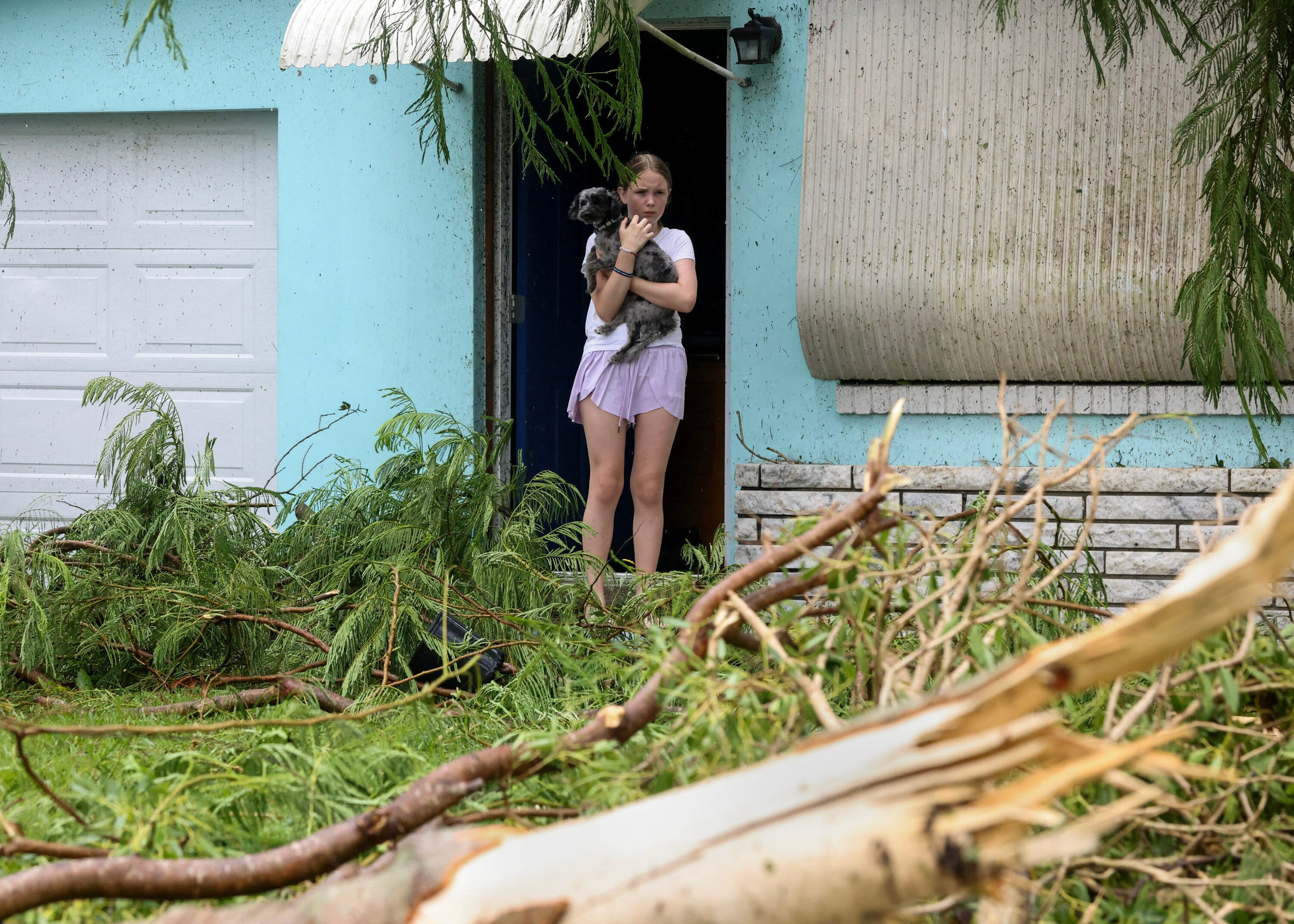 Mallory Tollett, 12, comforts her dog Maggie after a suspected tornado went through her family's property along Southeast Azimuth Way as Hurricane Milton bands move through Port Salerno, Florida, U.S., October 9, 2024. Crystal Vander Weit/USA TODAY NETWORK via REUTERS.