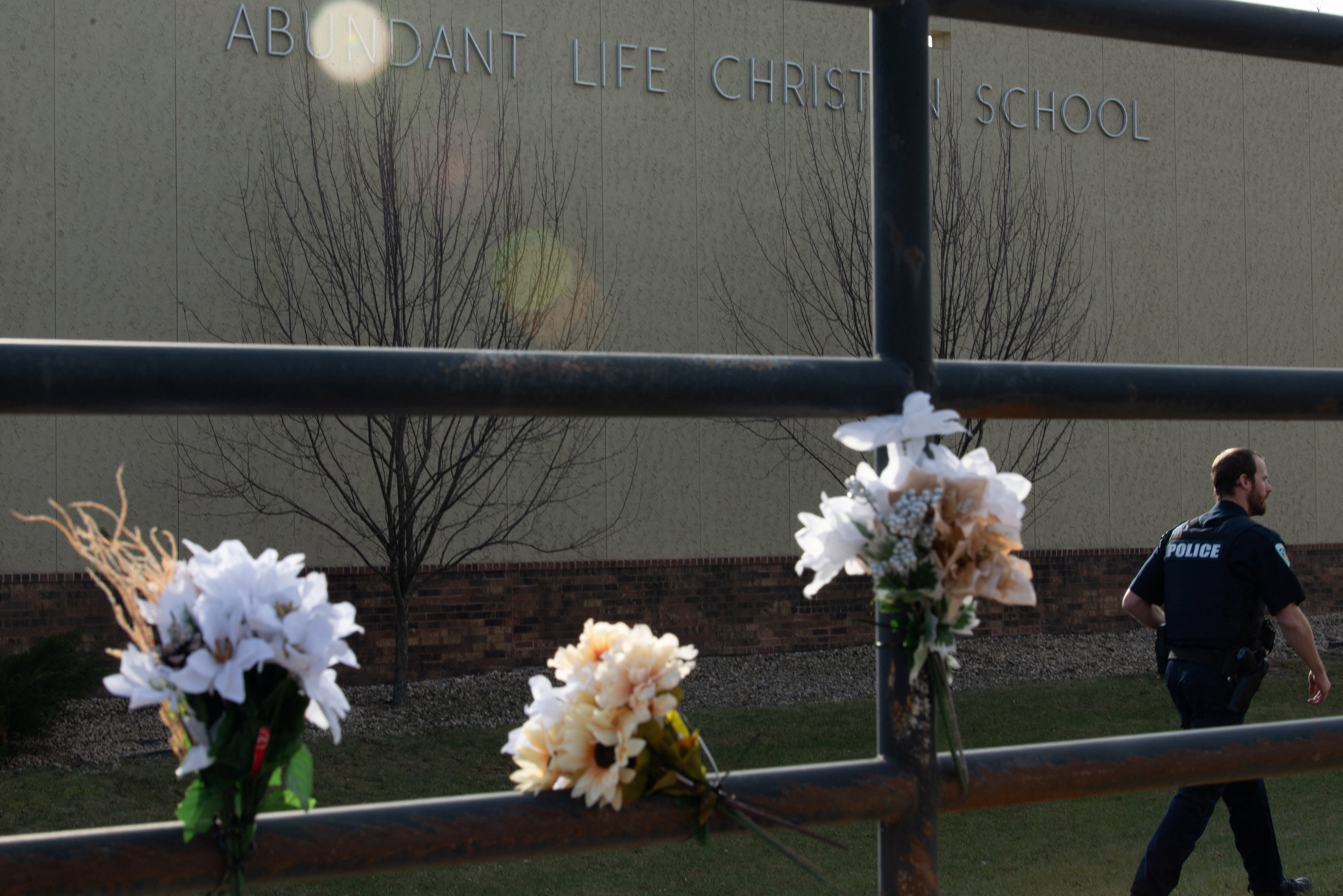 A police officer passes flowers left in memory of victims a day after a shooting at Abundant Life Christian School, in Madison, Wisconsin, U.S. December 17, 2024. REUTERS/Cullen Granzen