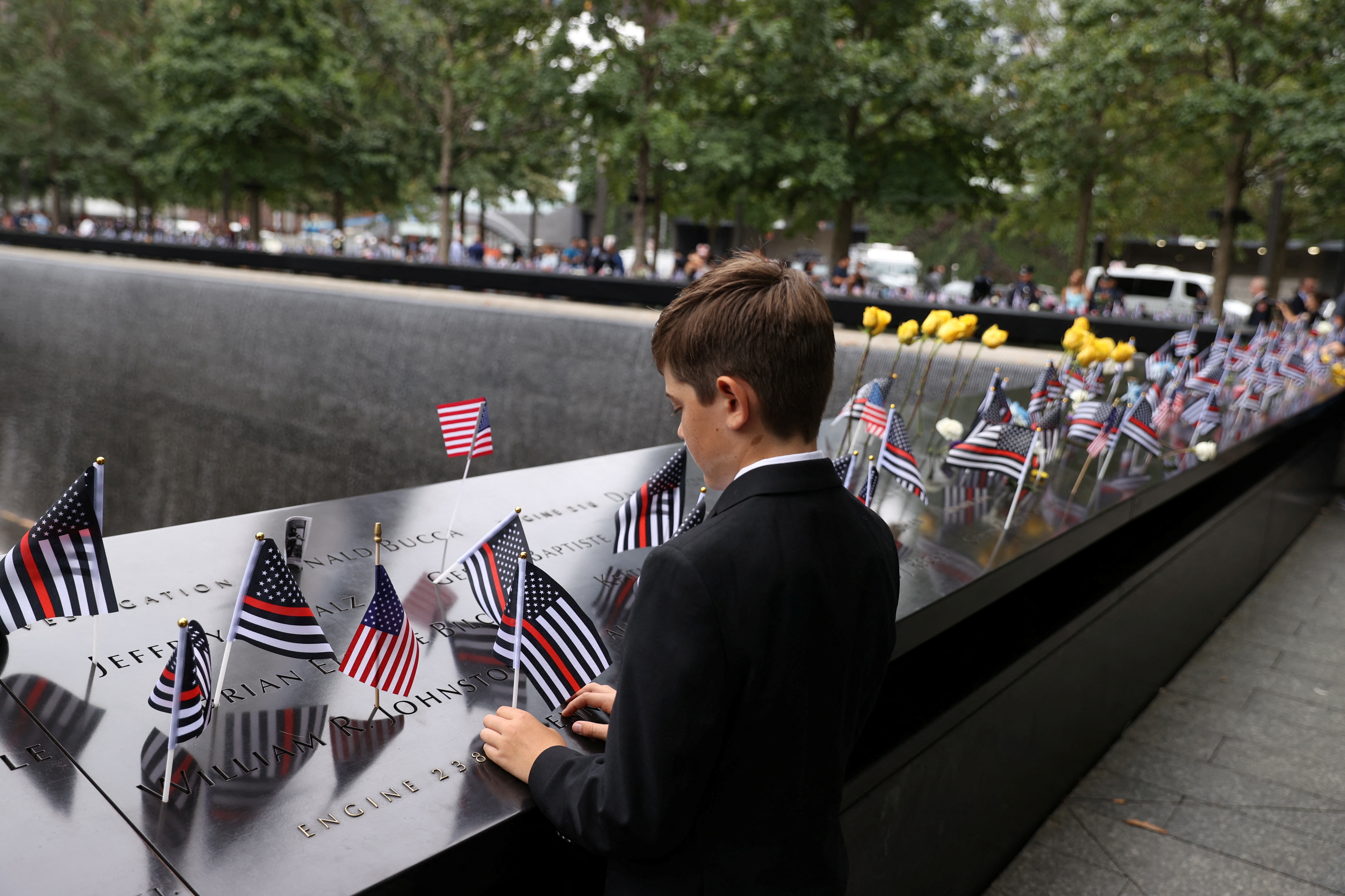 A boy places a flag during a ceremony marking the 21st anniversary of the September 11, 2001 attacks on the World Trade Center at the 9/11 Memorial and Museum in the Manhattan borough of New York City, U.S., September 11, 2022. REUTERS/Amr Alfik