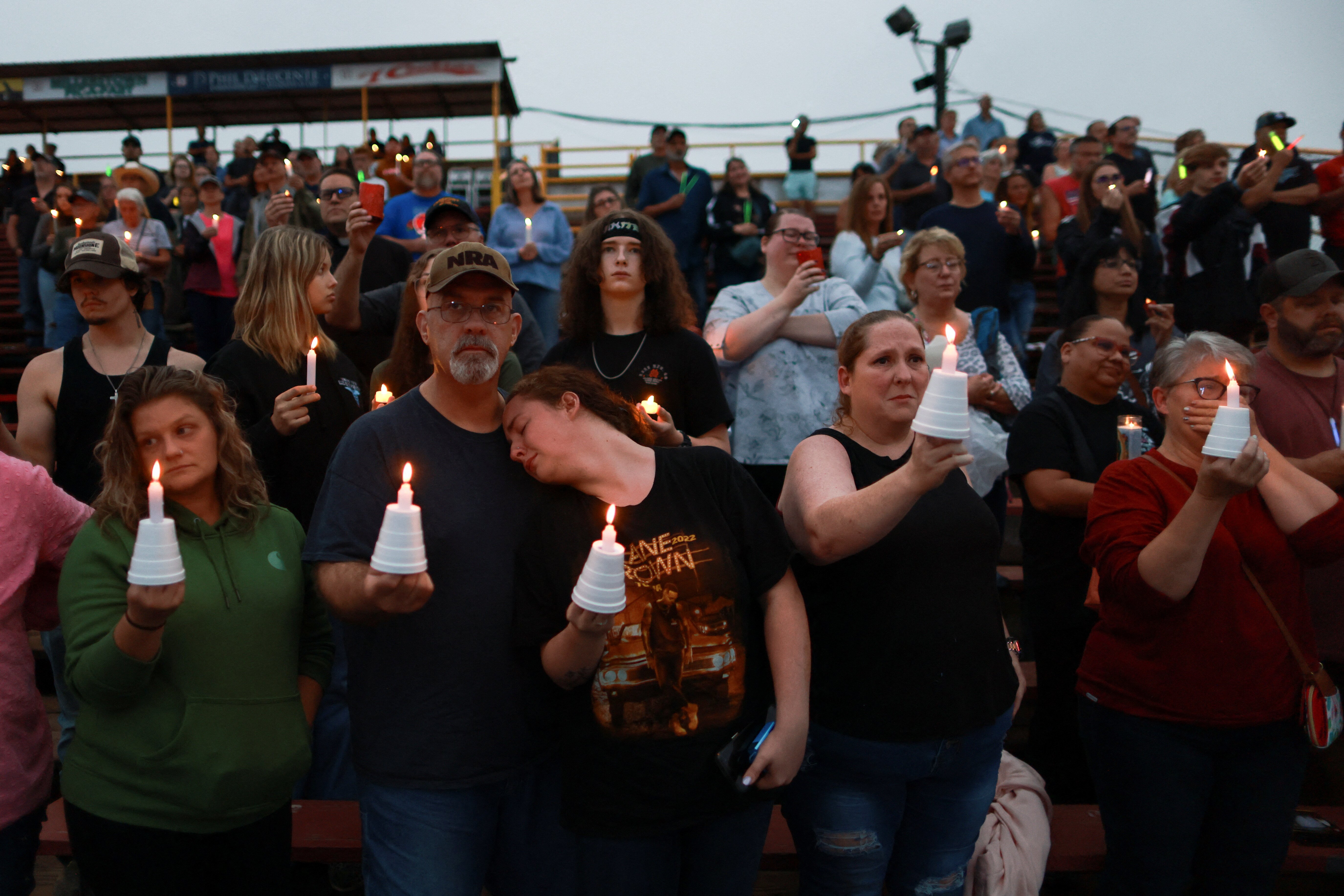 Dave Huston, who went to high school with Corey Comperatore, the former volunteer fire department chief killed at Republican presidential nominee Donald Trump's rally, and his daughter Becca Huston react as people hold candles during an event to honor Corey, at Lernerville Speedway in Sarver, Pennsylvania, U.S., July 17, 2024. REUTERS/Carlos Osorio