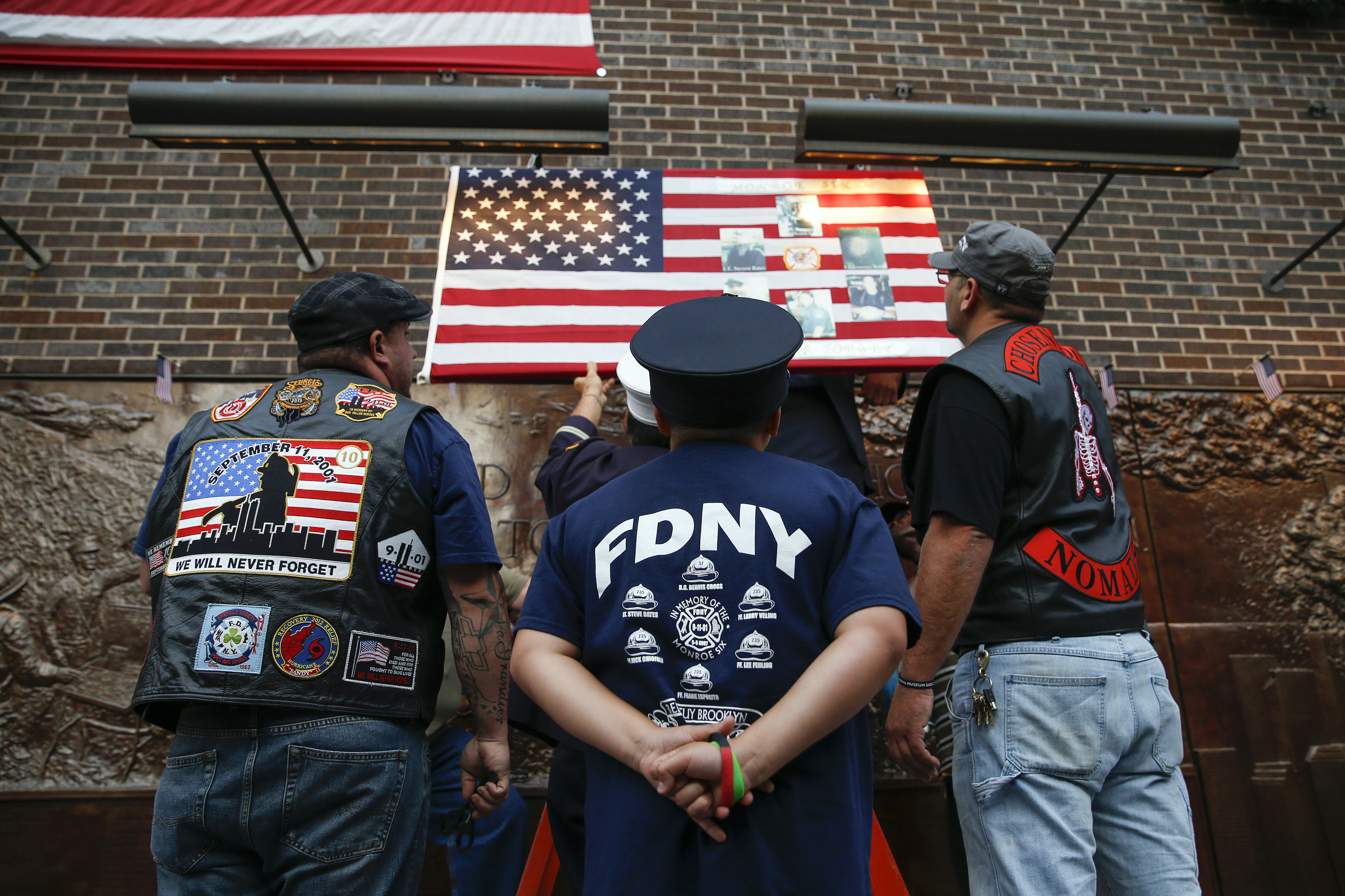 People hang a memorial U.S. national flag outside the New York Fire Department (FDNY) Engine Company and Ladder Company 10 near the 9/11 Memorial site, ahead of the 13th anniversary of the September 11 attacks, in New York, September 10, 2014. REUTERS/Shannon Stapleton