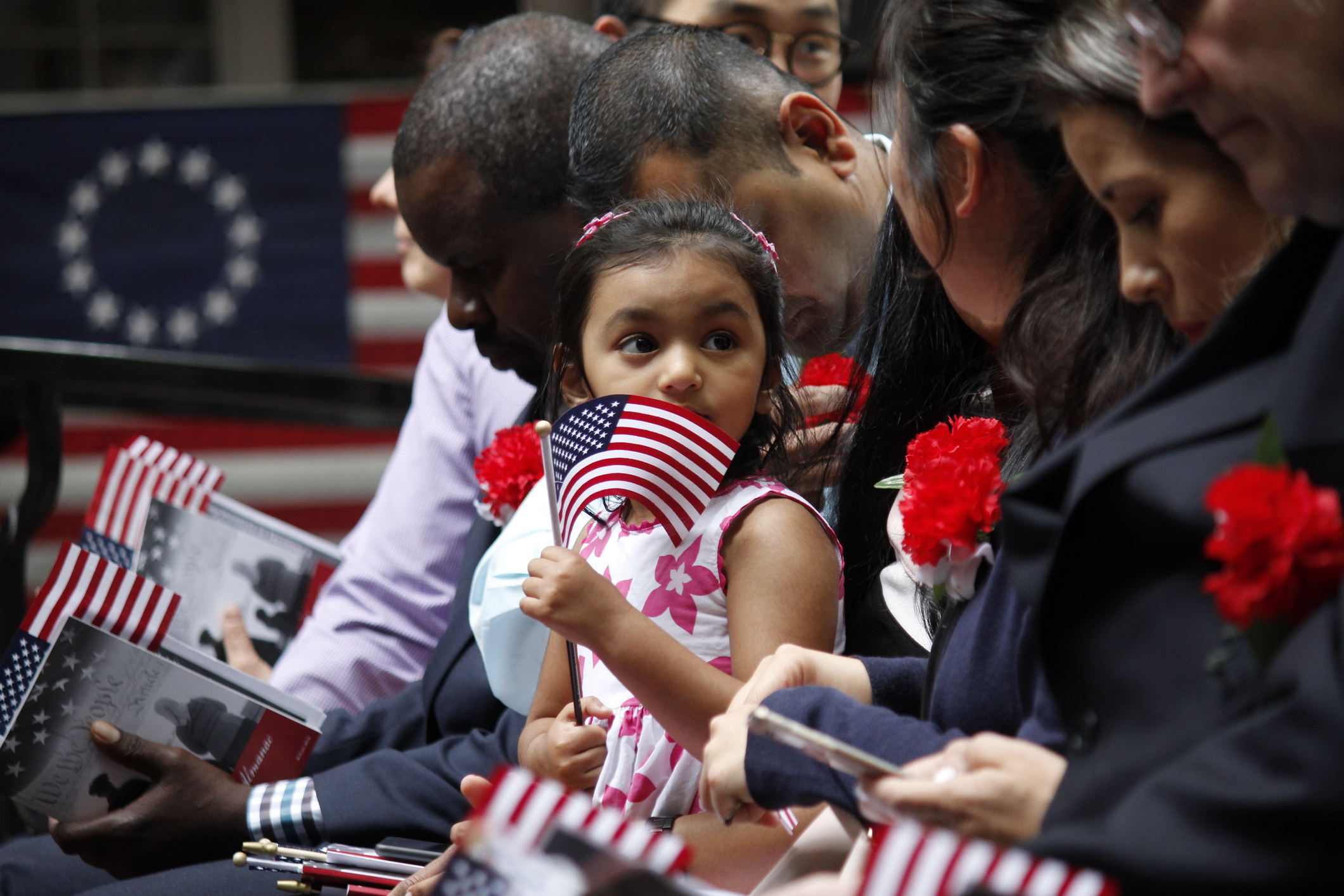 Philadelphia, PA, USA - June 14, 2019: The daughter of a immigrant holds an American flag while she joins her mother's naturalization ceremony on Flag Day at the historic Betsy Ross House in Philadelphia, Pennsylvania