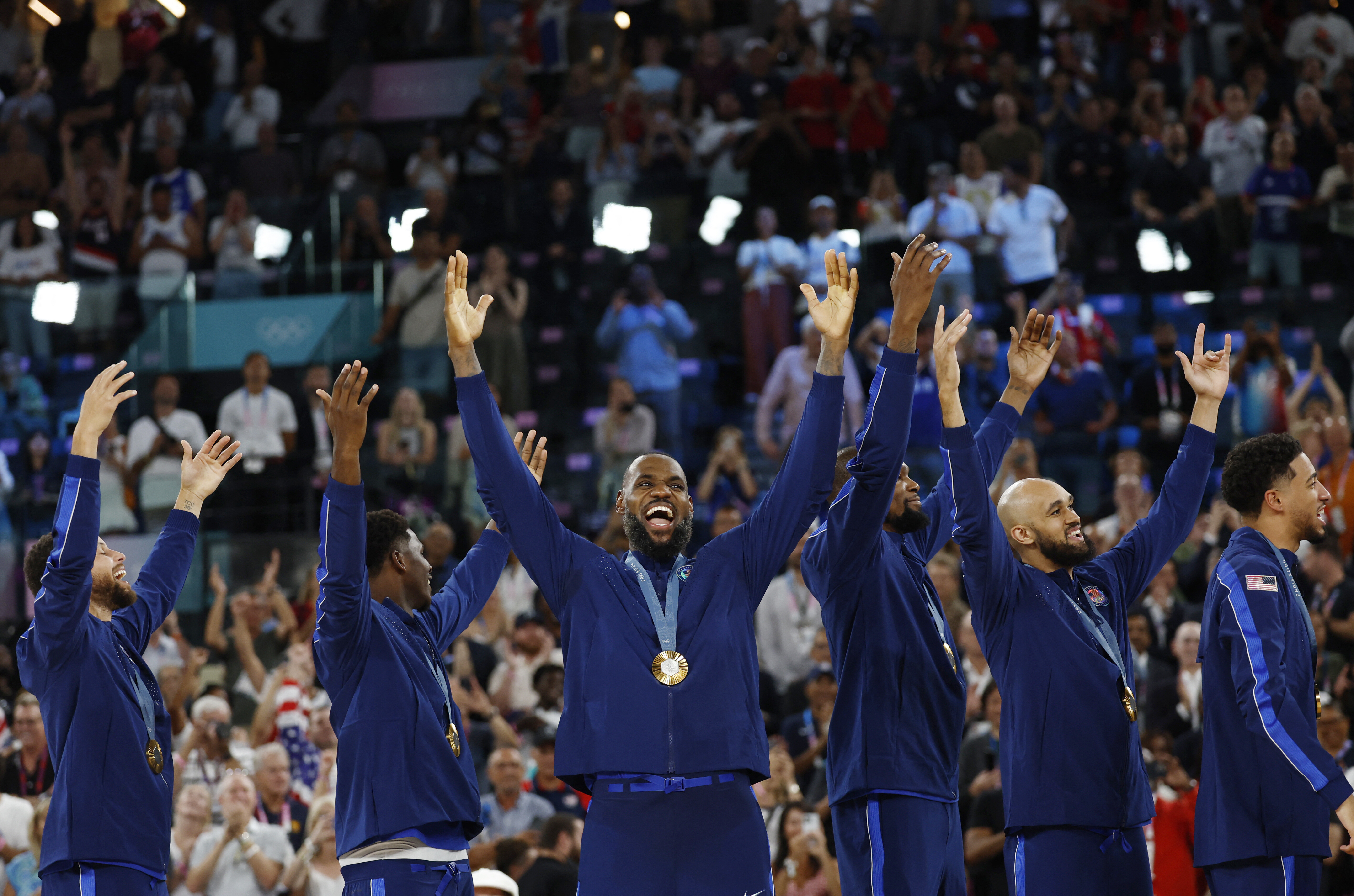 Paris 2024 Olympics - Basketball - Men's Victory Ceremony - Bercy Arena, Paris, France - August 10, 2024. Gold medallists Lebron James of United States, Stephen Curry of United States, Anthony Edwards of United States, Kevin Durant of United States, Derrick White of United States and Tyrese Haliburton of United States celebrate on the podium. REUTERS/Evelyn Hockstein