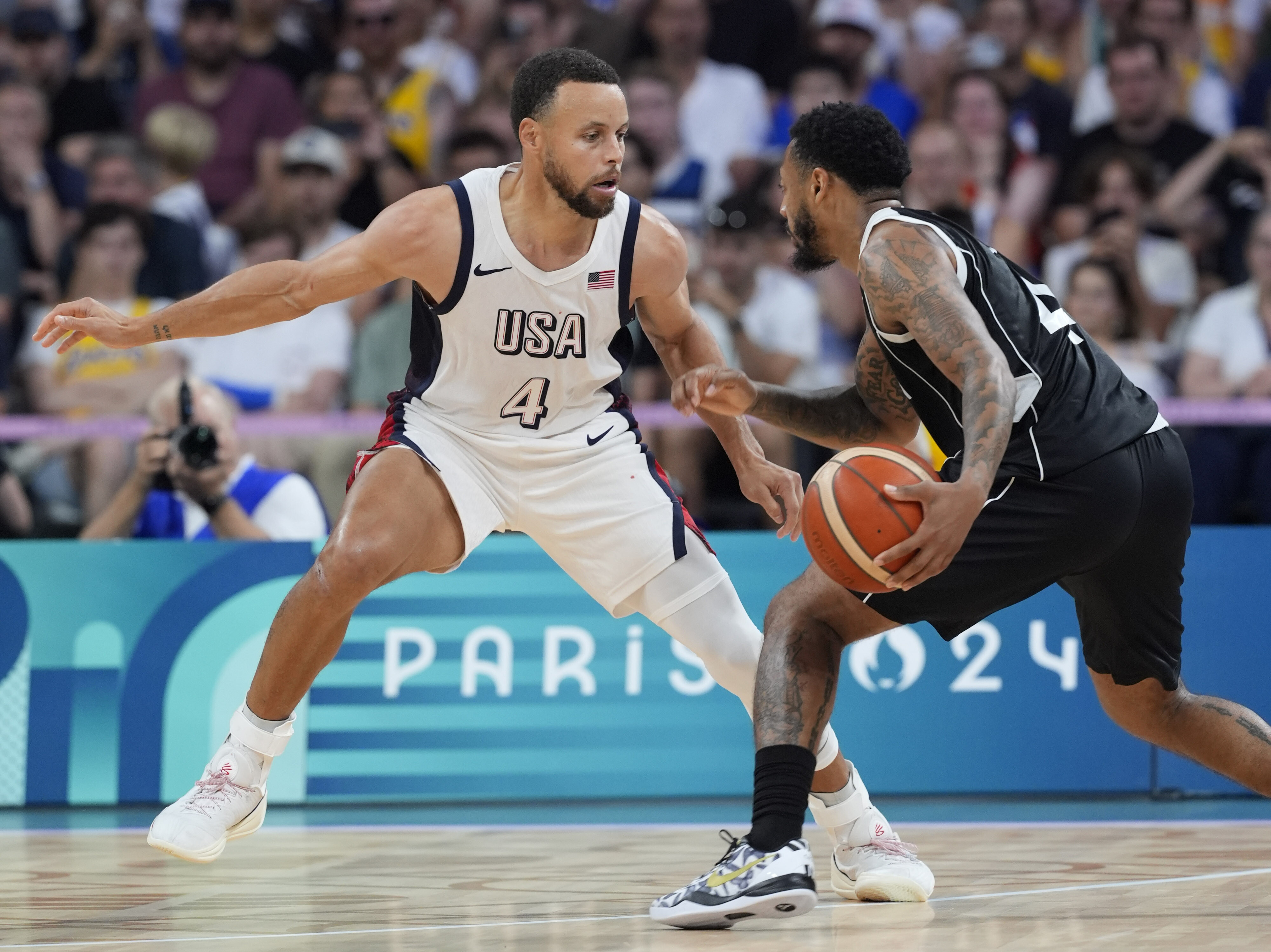 Jul 31, 2024; Villeneuve-d'Ascq, France; United States shooting guard Stephen Curry (4) defends South Sudan guard Carlik Jones (4) in the fourth quarter during the Paris 2024 Olympic Summer Games at Stade Pierre-Mauroy. credit: John David Mercer-USA TODAY Sports