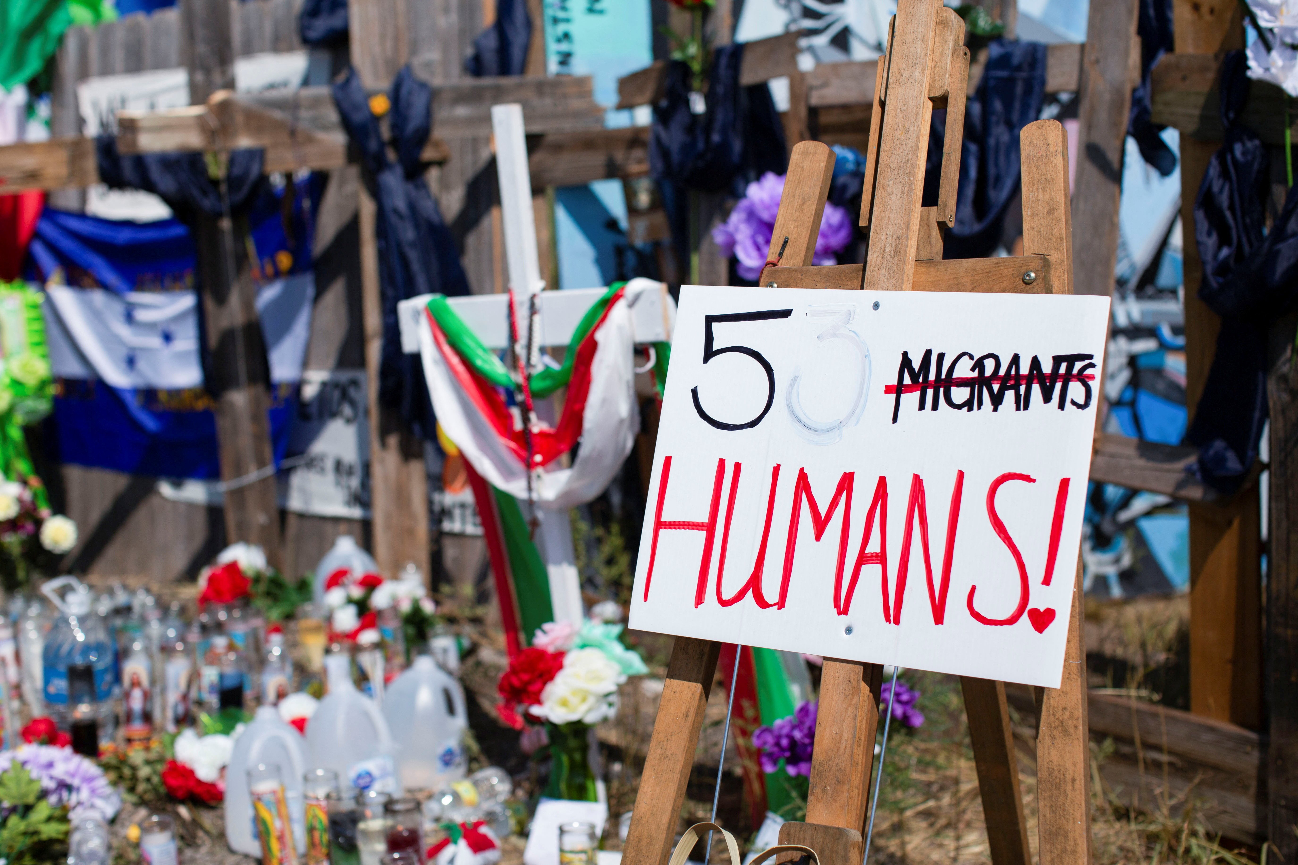 A view of a sign as community members pay their respects at a memorial set up for the migrants who were found dead inside a trailer truck in San Antonio, Texas, U.S. June 30, 2022. Several items including electrodes for EKG readings, various clothing items and water bottles were left scattered around where emergency services provided care. REUTERS/Kaylee Greenlee Beal